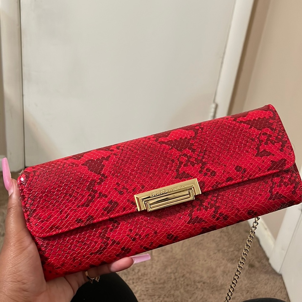 Red snakeskin BCBG clutch, with a gold crossbody chain.